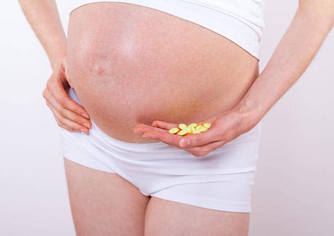 Pregnant woman holding pills